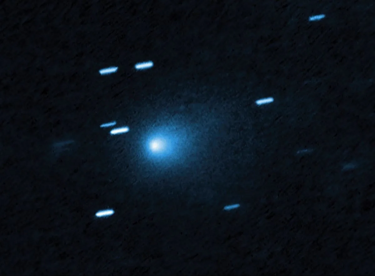 Cometa 3I/ATLAS com uma nuvem azulada de poeira, cercado por rastros de estrelas no registro do Hubble.